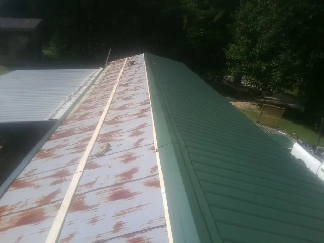 Old rusted panels beside newly installed green metal roofing — Wind Damage Roof Repair by Roofing Brothers in Elmore City