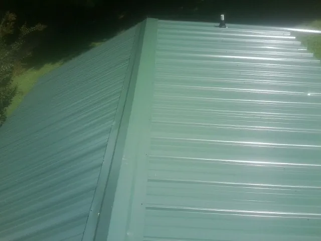 New green metal panels meeting at the ridge of a roof — Flat Roof Repair work by our crew in Elmore City