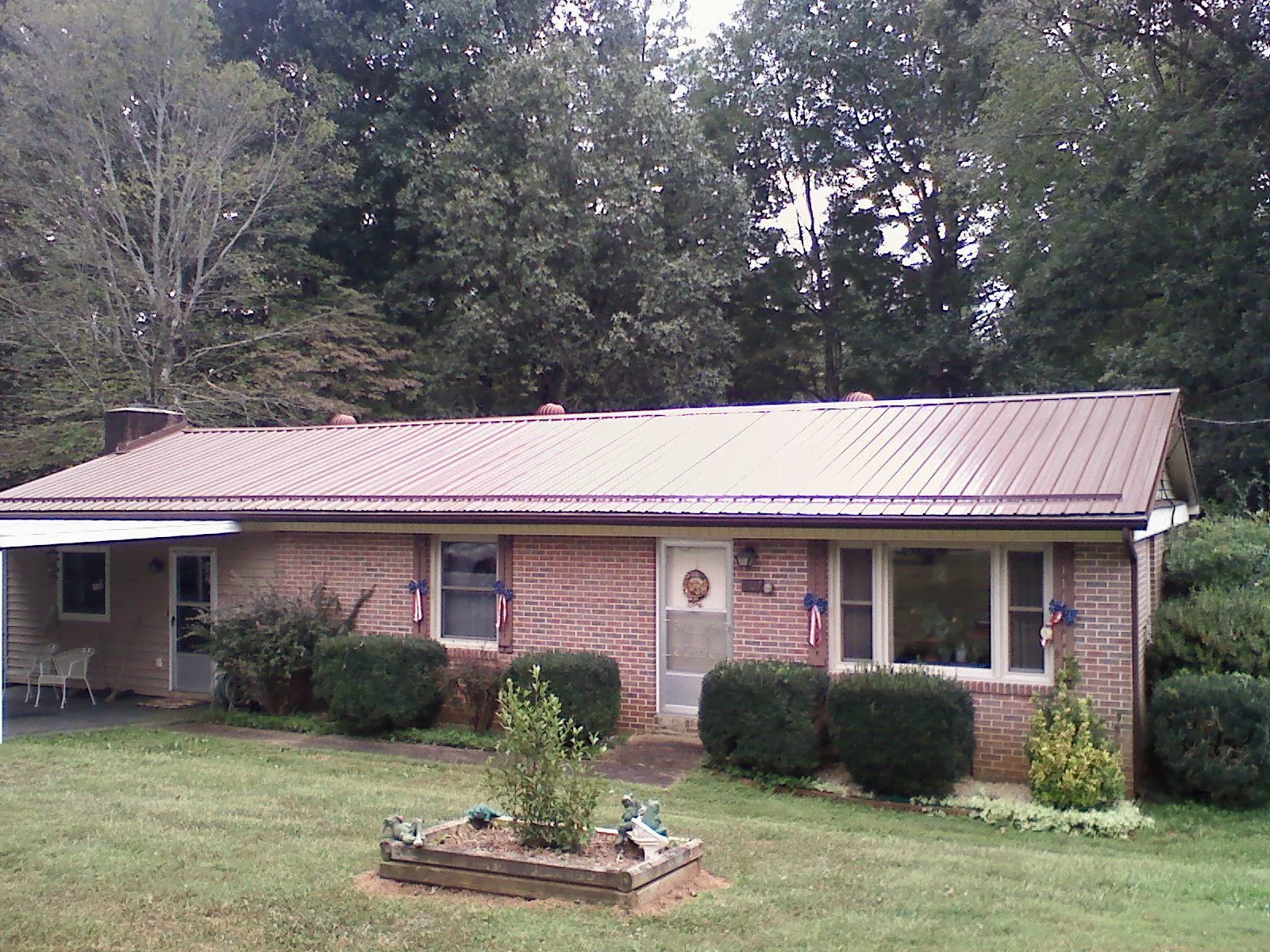 Bronze metal roof on a brick ranch home with a carport in Elmore City