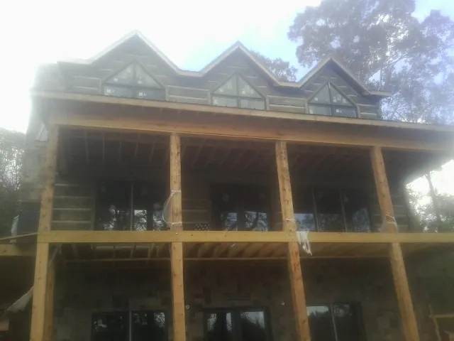 Dormers and porch framing on a large log home under construction — Roof Coating work by our crew in Elmore City