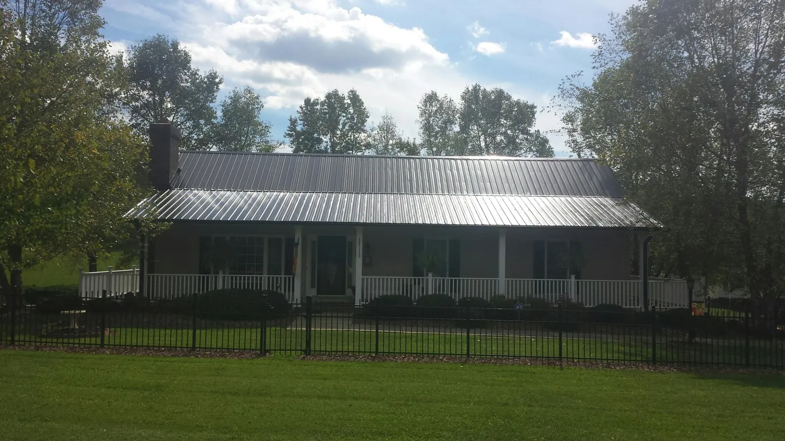 Gray metal roof on a brick ranch with a full width front porch — Gutter Guard Installation work by our crew in Elmore City