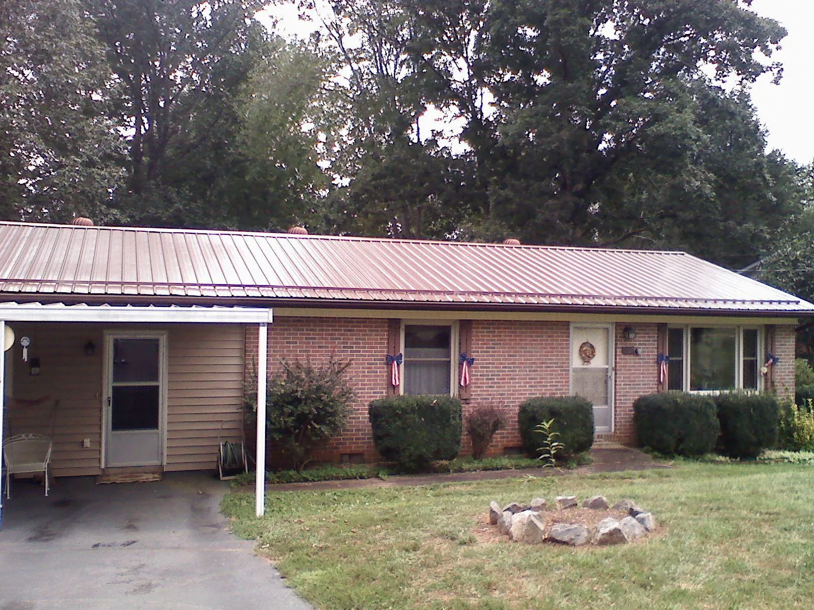 Bronze metal roof and carport on a brick ranch home — Roof Repair work by our crew in Elmore City